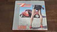 Front cover of ZZ Top Legs / Bad Girl 45 RPM single showing woman in black stockings and red heels with red car background