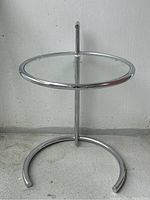 Chrome side table with circular clear glass top, adjustable height in lowest position.