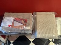 Two packaged carpet under pads sitting on a red surface and black and white tiled floor, showing overall size and packaging.