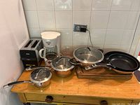 Photo of kitchen lot showing Henckels stainless steel pots and pans with glass lids, Black & Decker SmartBrew coffee maker, Silax toaster, and wooden cutting board