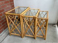 Front view of the three bamboo nesting tables stacked together, showing the glass tops and intricate bamboo craftsmanship.