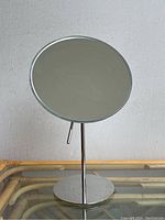 Front view of modern tabletop makeup mirror showing round reflective surface and chrome stand