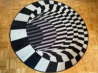 Full top-down view of round optical illusion rug showing complete pattern and colors.