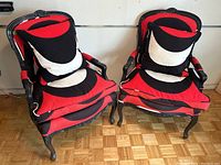 Pair of vintage bergere chairs painted black with bold red, black, and white Merimekko cushions and pillows.