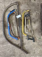 Overhead photo showing four different saws laying on a rough floor surface