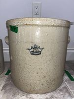 Full front view of beige speckled crock with a green sticker showing 12.5 and the blue crown emblem and number 3 on the front