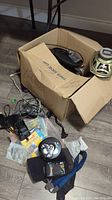 Cardboard box containing Kenwood speaker, assorted cables, and other electronics.