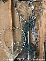 Photo showing three different sized fishing nets mounted on poles against a wooden wall background.
