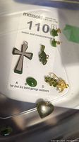 Overview of all jewelry items included in the lot showing cross pendant, heart pendant, beaver pendant, grape cluster with gold accents, leaf earrings, and jade stones.