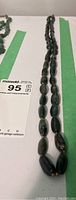 Photo of vintage dark green jade bead necklace laid out straight to show length and bead size variation.