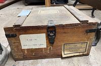 Wooden military ammunition box with metal latch and labels indicating 7.62mm pistol ammo.