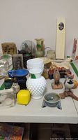 Wide view showing many figurines, milk glass vase, dice, and assorted decor items on a table.