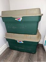 Two Rubbermaid storage totes stacked, showing beige lids and green bodies, with visible dirt and stains.