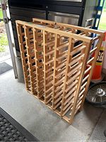 Photo of the wooden wine rack showing its front and side profiles, highlighting the grid design for bottle storage.