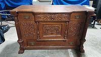 Front full view of the antique sideboard showing the intricate carvings and brass handles.