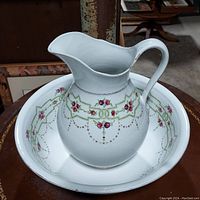 Large white ceramic pitcher with handle and spout featuring pink rose and green geometric floral design inside a matching large bowl