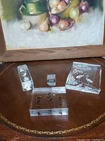 Four glass decorative pieces on table: three etched with animal scenes and one solid glass block with inset seahorses