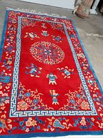 Full view of the 5x8 oriental rug showing vibrant red background with intricate traditional patterns and blue border.