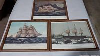 Three framed sailboat prints on a flat surface showing all three ships with wood-look frames.