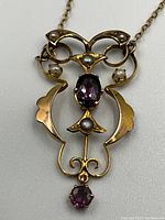 Close-up of pendant front showing filigree design, amethyst center and seed pearls