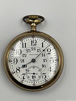 Front dial view showing white enamel face, Arabic numerals, subsidiary seconds at 6 o’clock, blued steel hands.