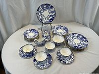 Overhead view of full Blue Willow dinnerware set arranged on white cloth.