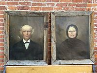 Overall view of both framed portraits displayed side by side against a brick wall