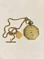 Overall view of gold filled pocket watch with chain, T-bar and fob pendant