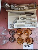 Top view showing glassware including clear and amber glasses with cutlery and kitchen utensils in trays.