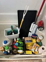 Overview of assorted household cleaning supplies and tools including bottles, boxes, dustpans, and cloths