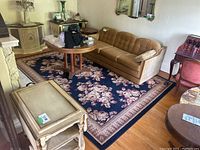 Navy blue area rug with floral design placed under living room furniture.