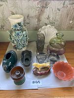 All miscellaneous vases and decorative items on white cloth, includes various vases, candle holders, bowls and figurines.