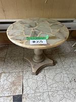 Front view of round mosaic stone side table on pedestal base.