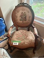 Front view of vintage needlepoint accent chair showing detailed upholstery and carved wood frame.