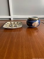 Photo showing square plate with Egyptian motifs and small rounded mug with Egyptian style decorations.
