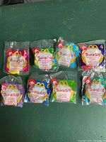 Photo showing complete set of eight Tamagotchi Happy Meal toys in original sealed blister-style packaging with McDonald's branding and numbers 1 to 8.