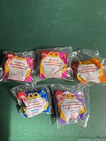 Front view of five sealed McDonald's Animal Pals 1997 Happy Meal toys in original packaging, showing unopened clear plastic bags with colored labels and toy outlines visible inside.
