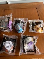 Six sealed Beauty and the Beast McDonald's Happy Meal toys from 2002 set on wooden surface, front side with brand and character details visible through packaging.