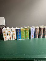 Side view of boxed Disney Happy Meal toys showing 14 sets in total with original packaging, varying conditions, stacked inline on table