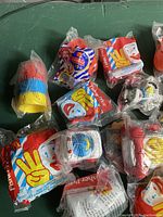 Close-up image showing multiple mini Fisher Price toys in sealed original Happy Meal packaging, featuring bright colors and Ronald McDonald branding.