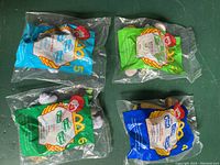Four original McDonald's Happy Meal toys from House of Mouse 2001 sealed in plastic bags, showing tops with character numbers and McDonald's branding.