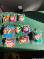 Photo showing all 8 toys from 1999 McDonald's Tarzan Happy Meal set plus additional 2000 Toy #4, all sealed in original packaging.