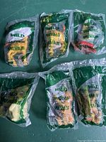 Six McDonald's The Wild 2006 Happy Meal toys, sealed in original green and clear plastic packaging, displayed on a green surface. The packaging shows character images and labeling in English and Spanish.