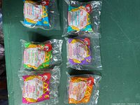 Sealed McDonald's Happy Meal toy packages showing front side with numbered labels and colorful branding.
