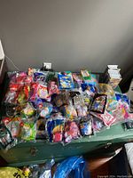 Top-down photo showing a large spread of various Happy Meal toys in original packaging laid out on a table.