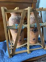 Front view of two Indonesian terracotta pots inside a wooden frame, showing the detailed geometric patterns and structure of the frame.