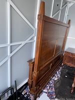 Side angle showing headboard, solid wood panels, carved corner posts, and lower long panels
