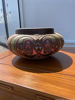 Side view showing the painted geometric and tribal design on the bulging body of the pot, highlighting colors and pattern details.