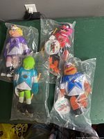 Four Muppets NHL Conference plush dolls in original plastic packaging, two standing upright, two laying down, visible are Miss Piggy, Kermit, Animal, and Fozzie Bear.