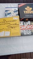 Five board games laid out on a table including Monopoly Doctor Who, 100% Canadian Trivia, The Worse Case Scenario, Classic Dominos, and Monopoly Doctor Who edition.